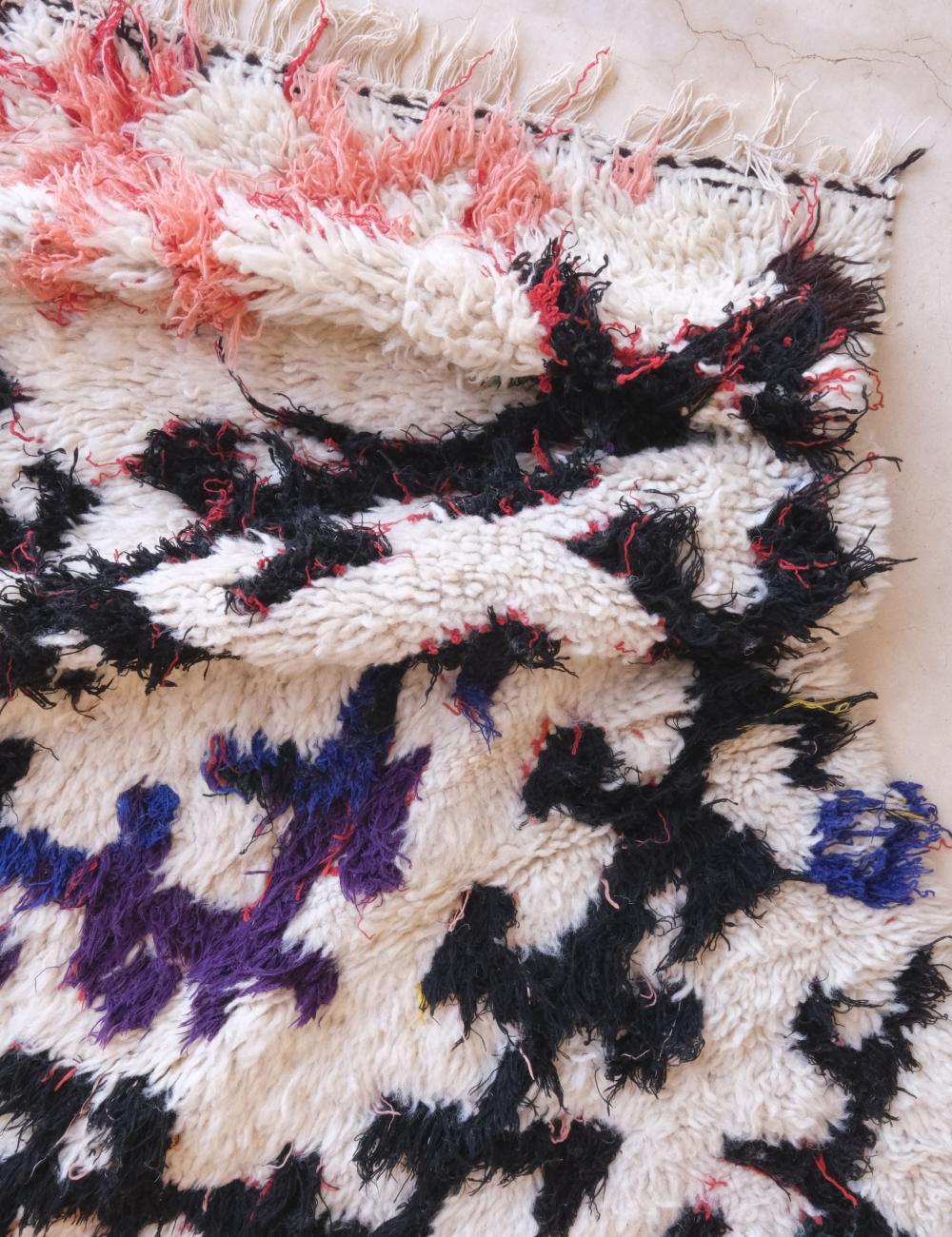 Close-up of a textured fabric with black, white, pink, and blue patterns.