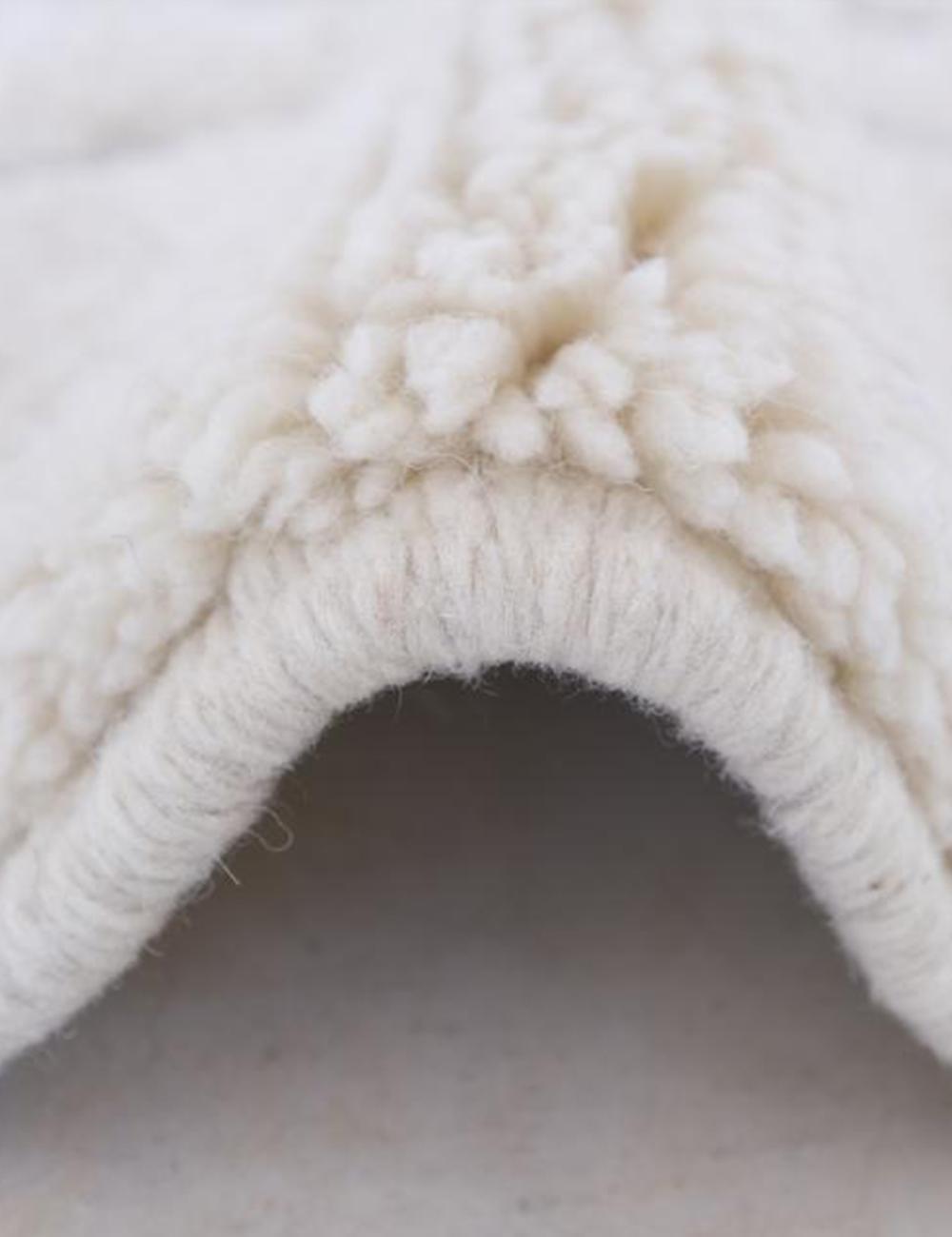 Close-up of contemporary Moroccan Beni Mrirt wool rug showing thick soft white pile and folded texture.