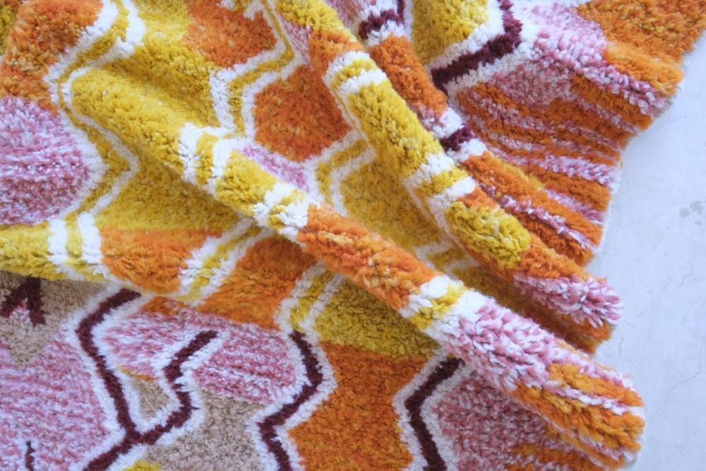 Close-up of modern Moroccan Boujad wool rug with vibrant yellow, orange, and pink zigzag geometric patterns and thick soft pile.