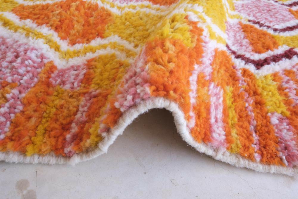 Close-up of modern Moroccan Boujad wool rug with thick pile, showing vibrant yellow, orange, and pink zigzag geometric patterns.