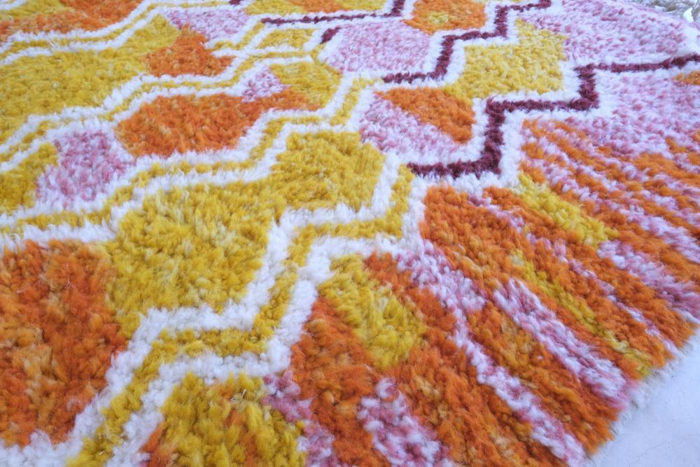Close-up of modern Moroccan Boujad wool rug with thick pile and vibrant zigzag patterns in yellow, orange, pink, and burgundy.