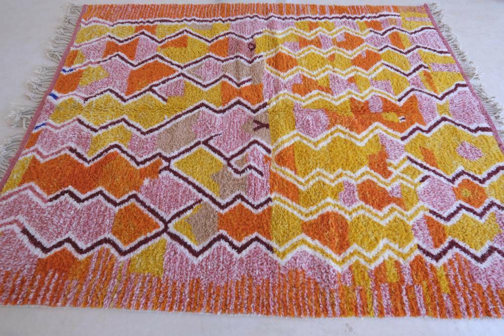 Modern Moroccan Boujad wool rug with vibrant pink, yellow, and orange zigzag geometric patterns and fringed edges.
