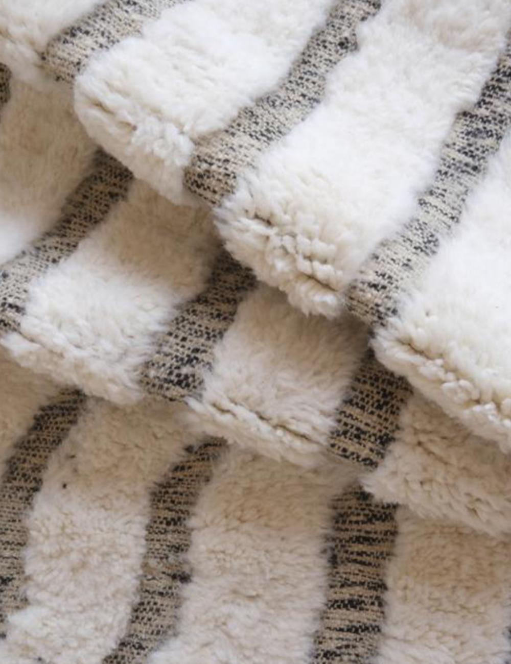 Folded Moroccan Beni Ourain wool rug with thick white pile and black stripe pattern