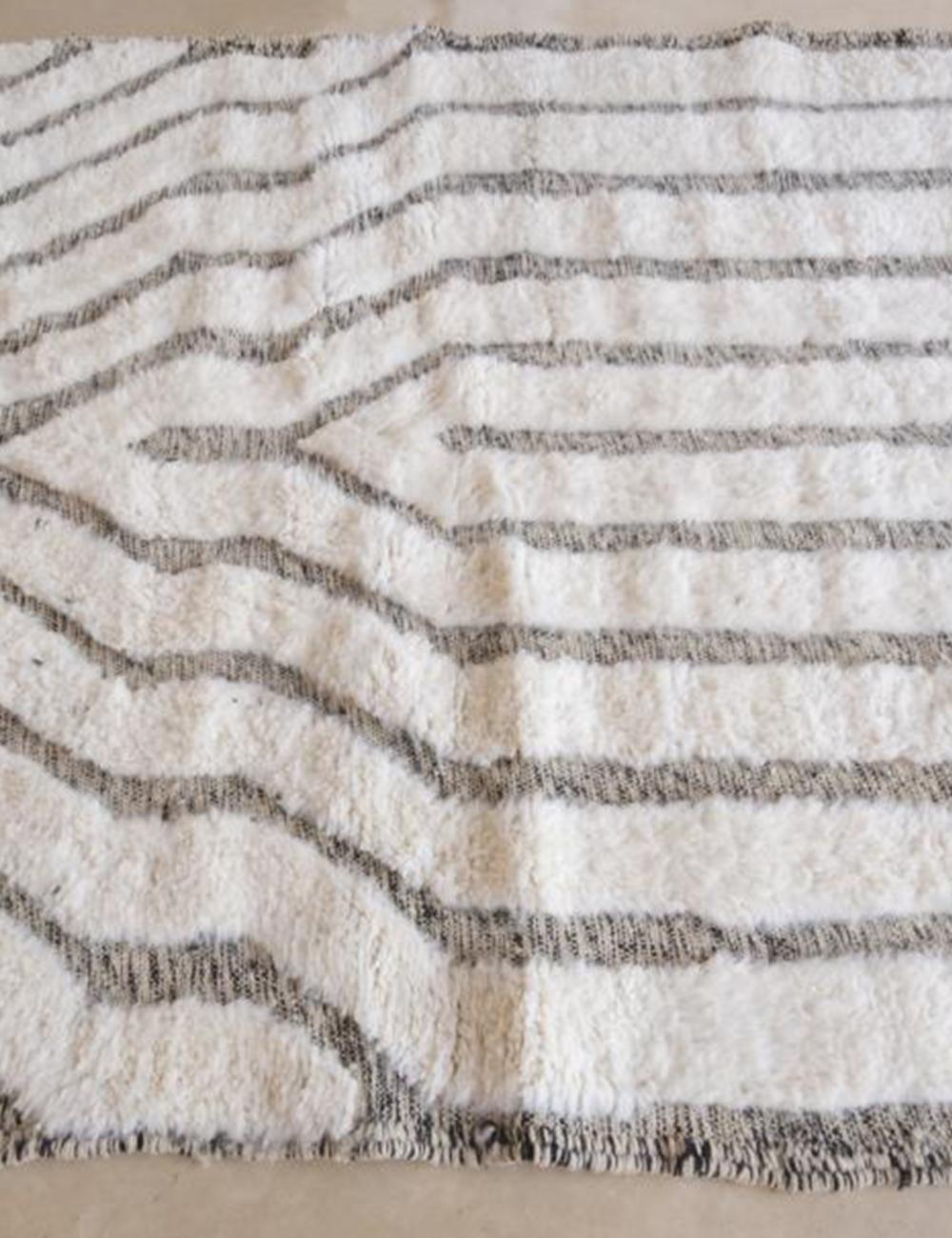Handwoven Moroccan Beni Ourain wool rug with black horizontal stripe pattern on a cream background.