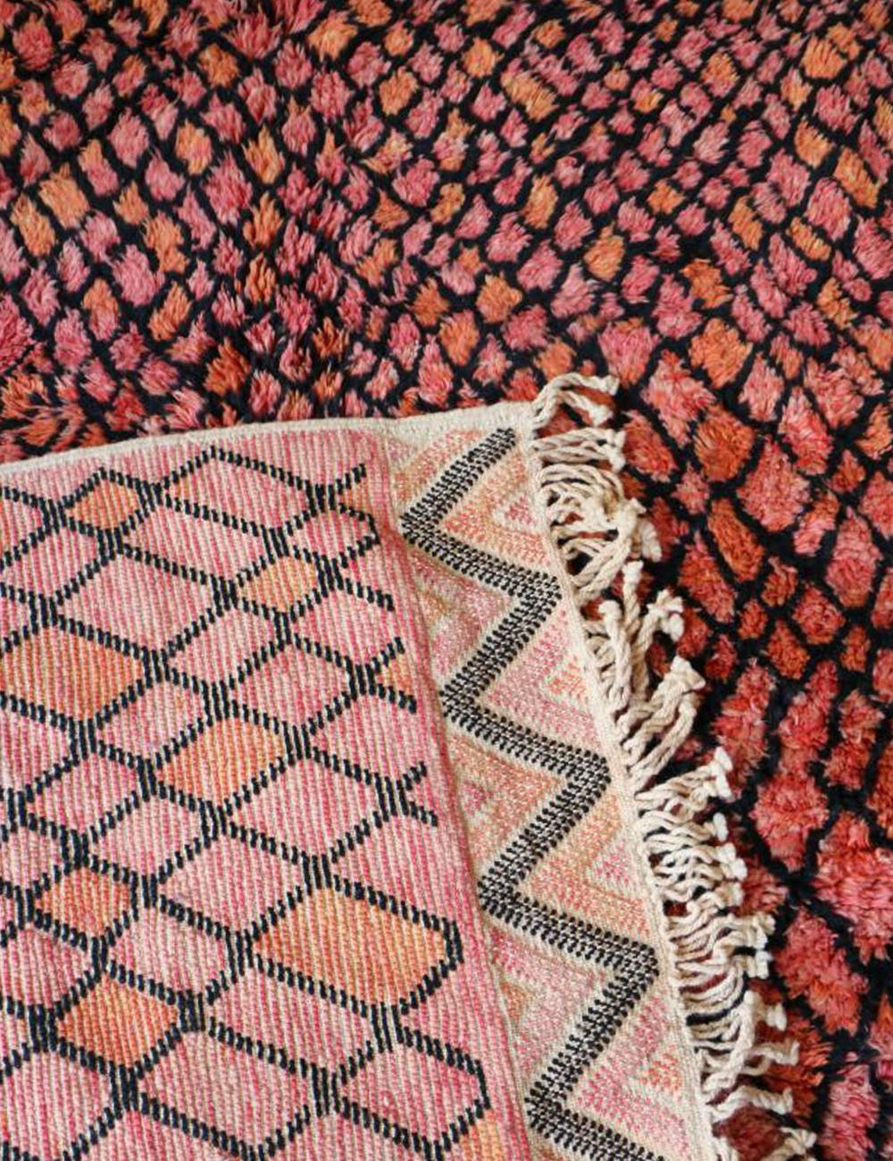 Close-up of a patterned rug with pink, black, and orange colors.