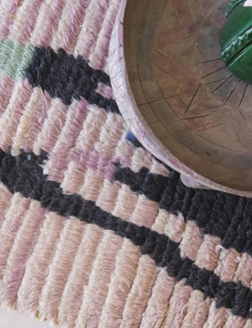 Close-up of a textured rug with geometric pattern and a metal object on top.