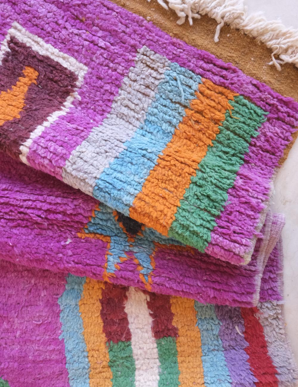 Colorful textured rug with geometric pattern on a wooden floor.