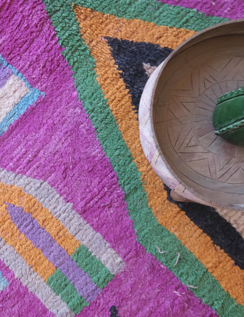 Close-up of a colorful geometric-patterned rug with a woven basket on top.
