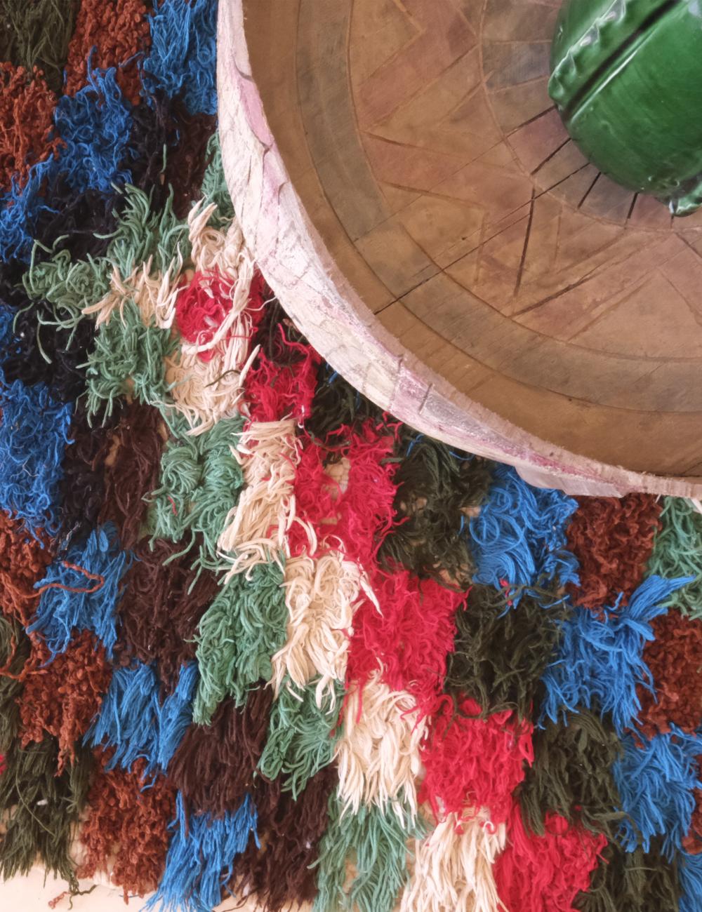 Colorful crocheted blanket with a wooden bowl and green object on top