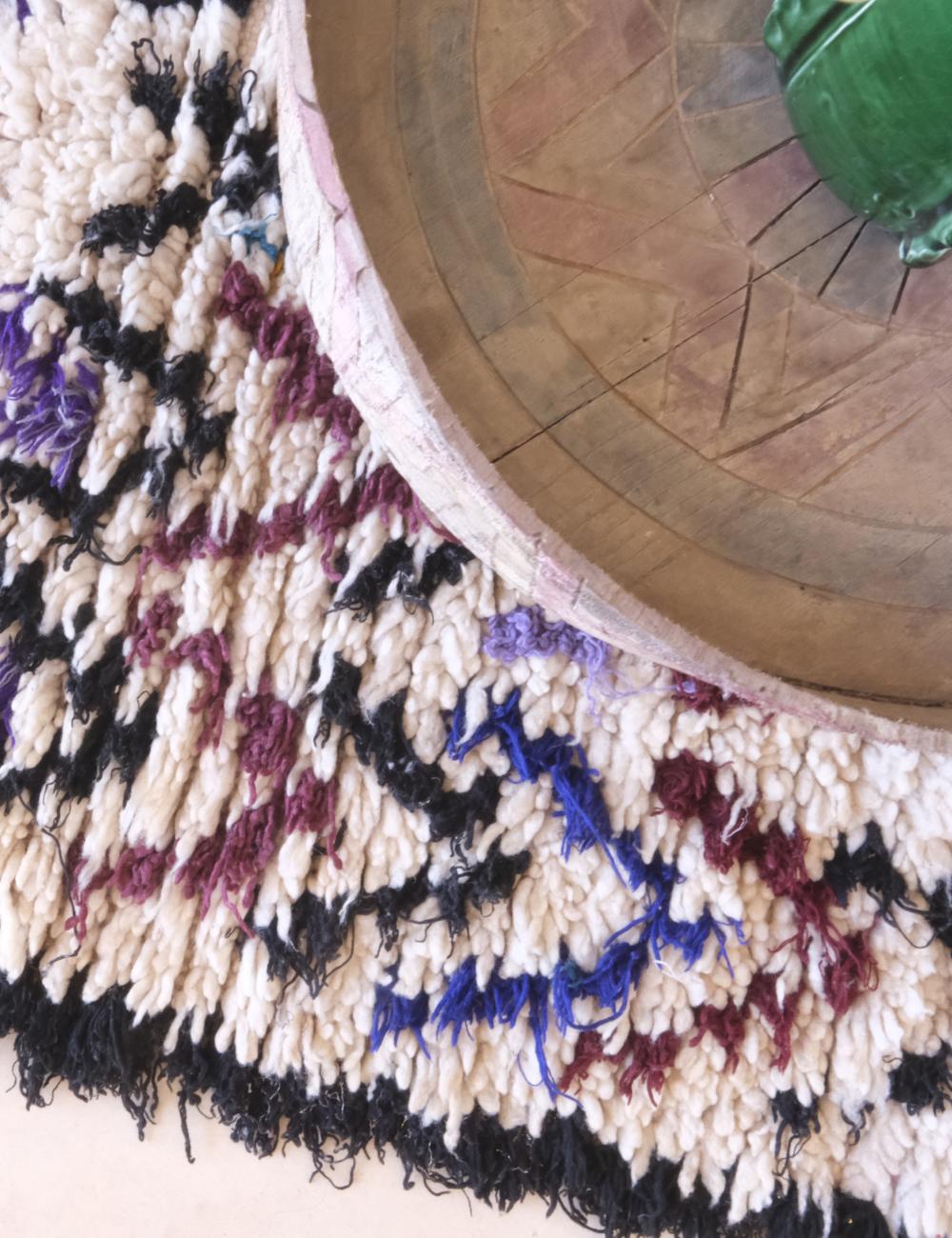 Close-up of a textured rug with colorful patterns on a wooden floor.