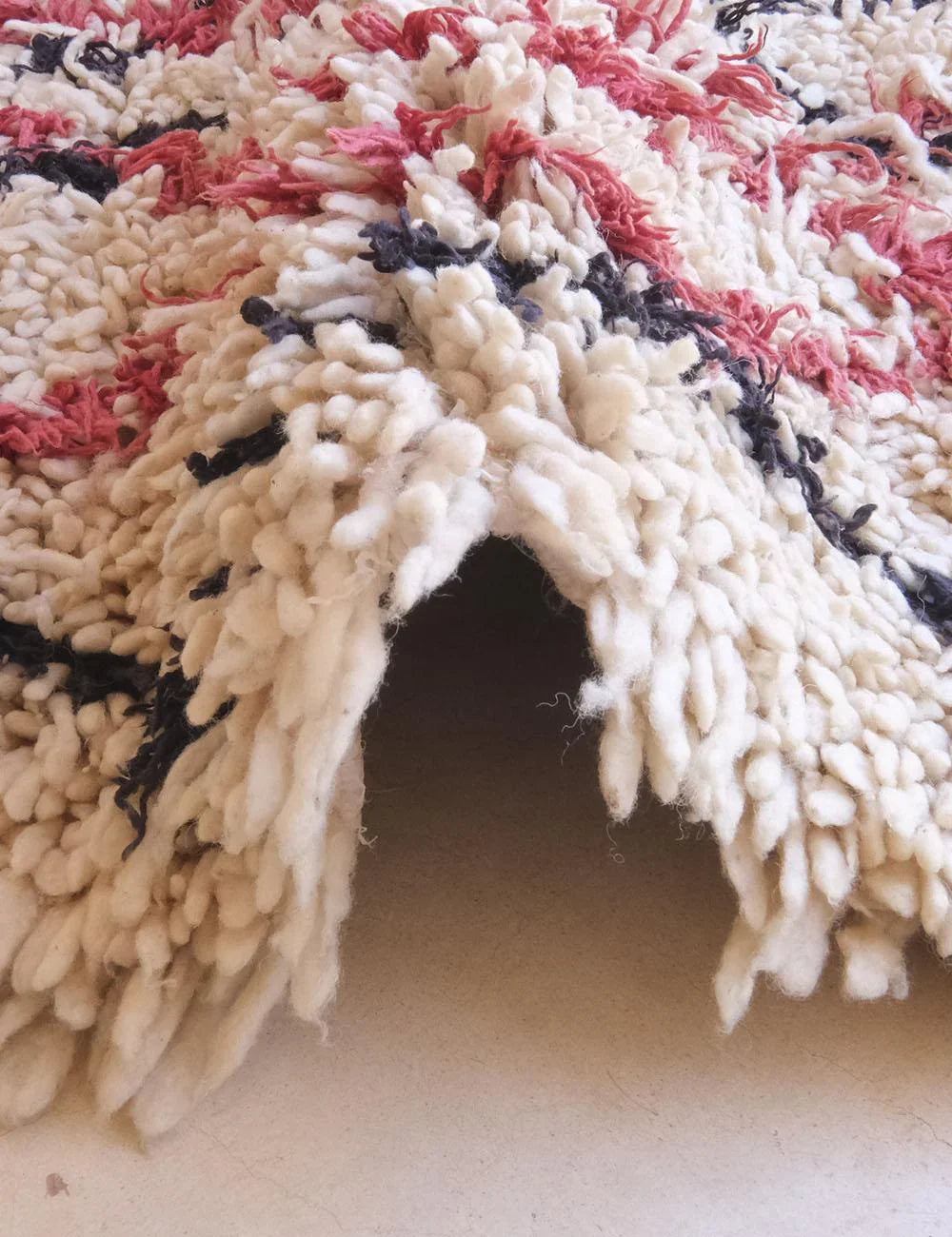 Close-up of a textured rug with red, black, and beige patterns.