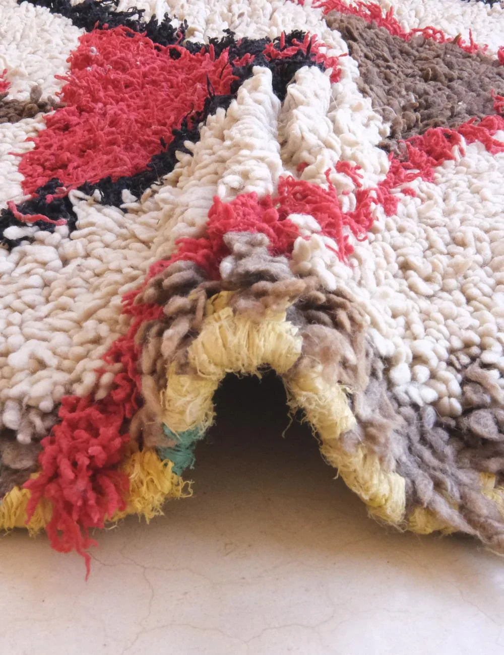 Close-up of a textured, multicolored fabric with red, black, and beige patterns.