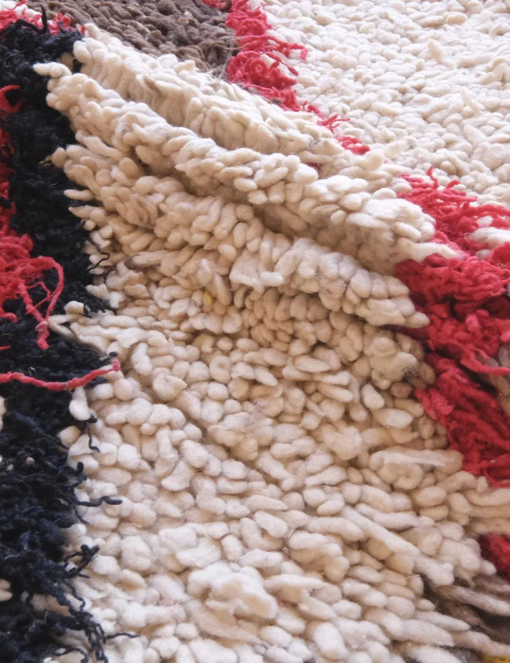 Close-up of a textured rug with black, red, and beige colors.