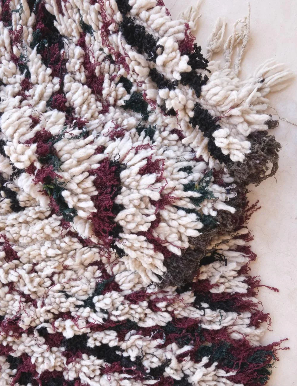 Close-up of a textured rug with a pattern of white, red, and black.