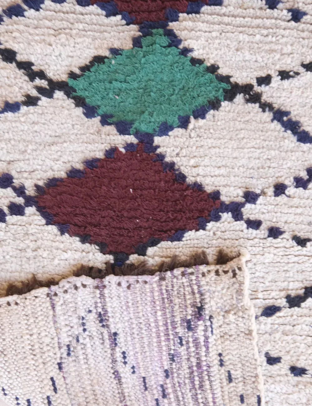 Close-up of a textured fabric with geometric pattern featuring green, red, and blue colors.