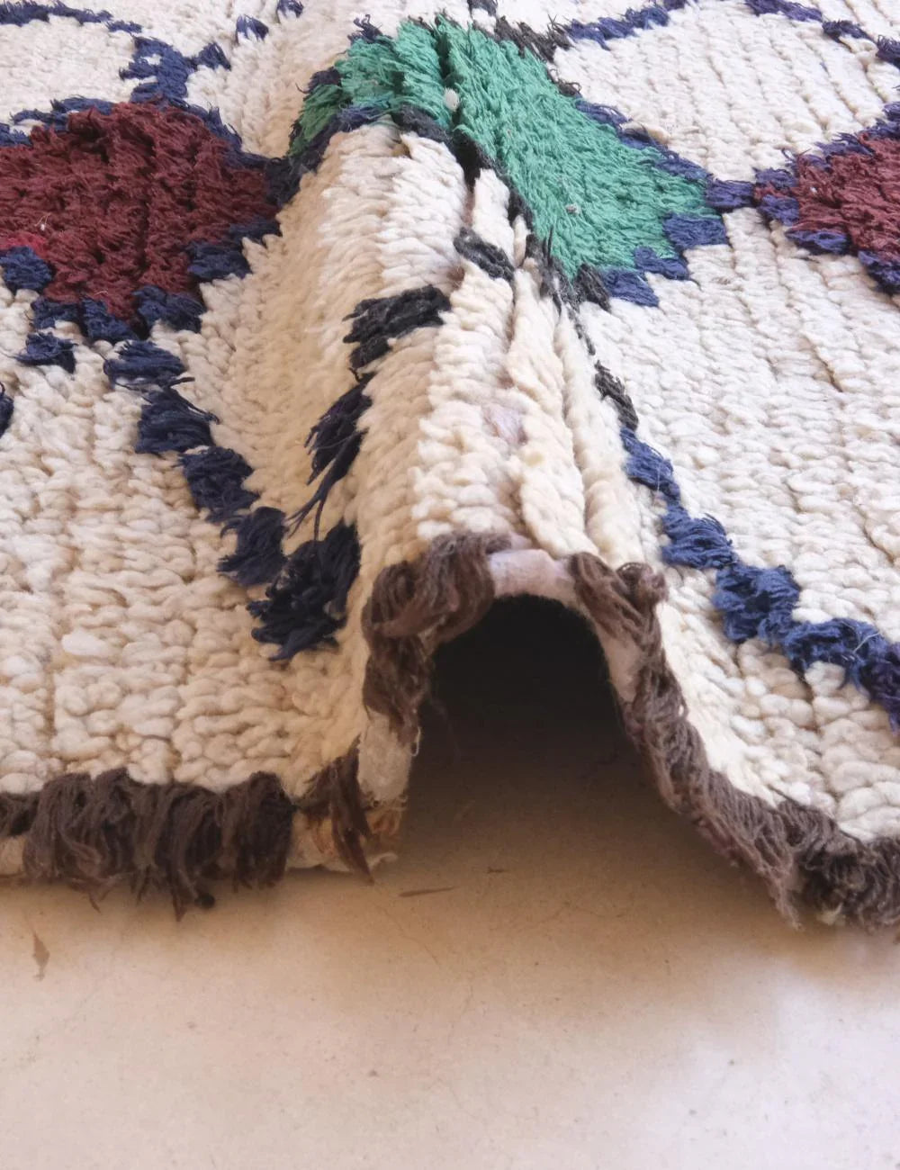 Close-up of a textured rug with geometric pattern on a light-colored floor.