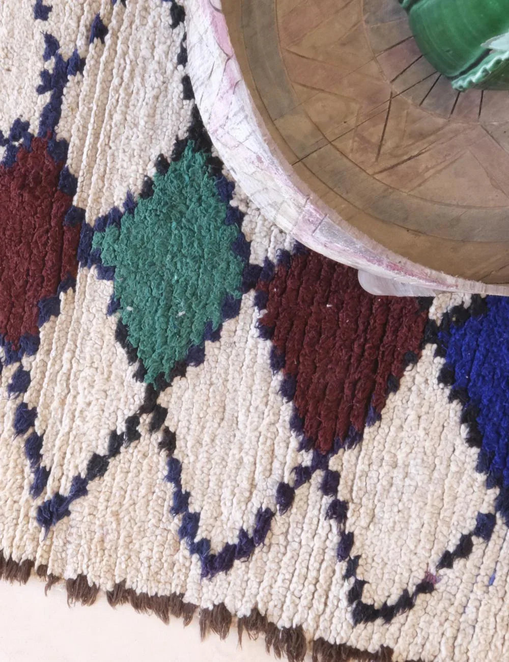 Close-up of a patterned rug with geometric design, showing a wooden chair leg.