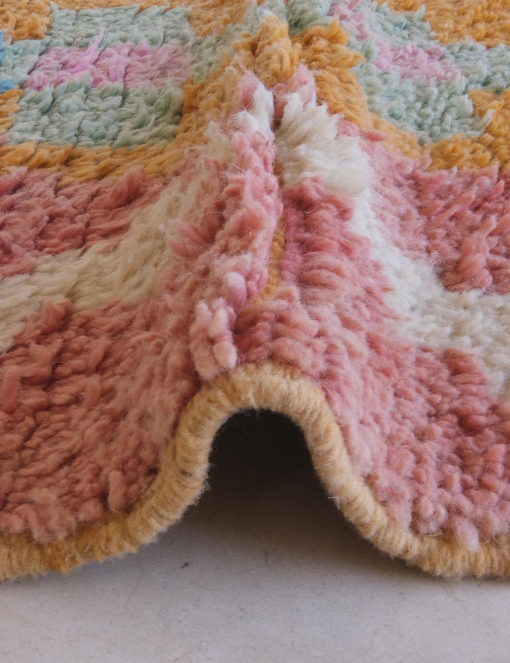 Close-up of a textured pink and orange rug corner.