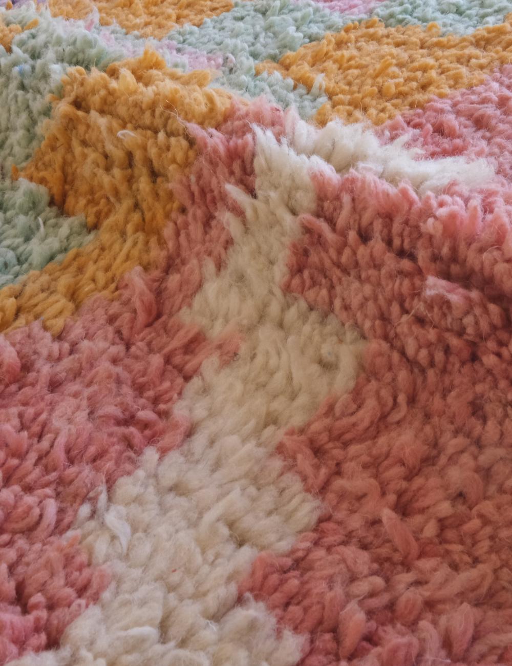Close-up of a textured, multicolored rug with a wavy pattern.