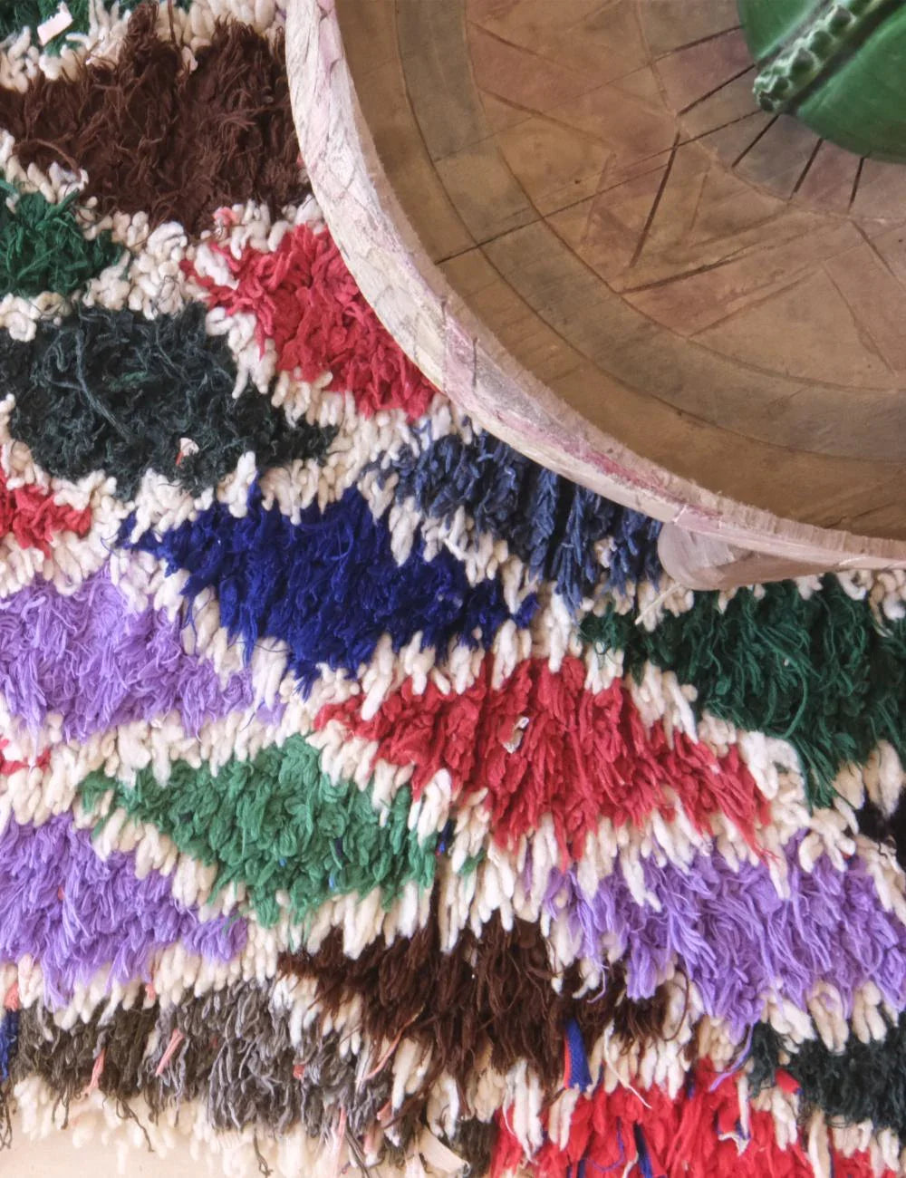 Colorful textured rug with a wooden wheel on top
