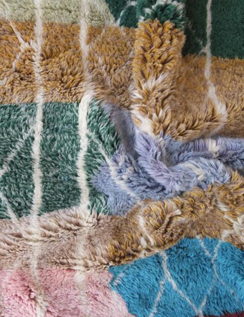 Contemporary Moroccan Beni Mrirt wool rug with multicolor geometric squares and white lattice pattern, folded corner showing striped backside with fringes.