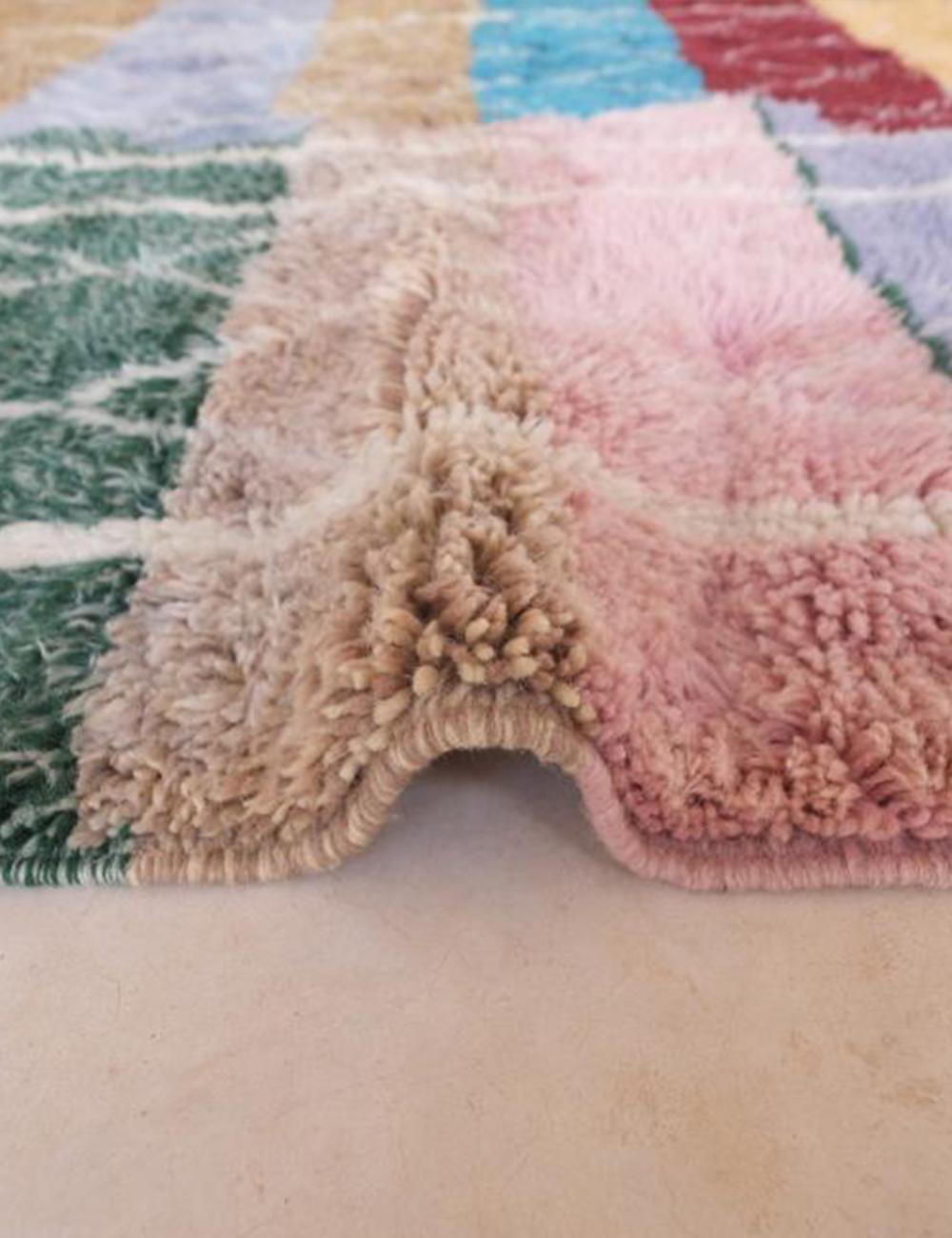 Close-up of contemporary Moroccan Beni Mrirt wool rug with multicolor geometric squares in green, beige, pink, and burgundy, showing thick soft pile.