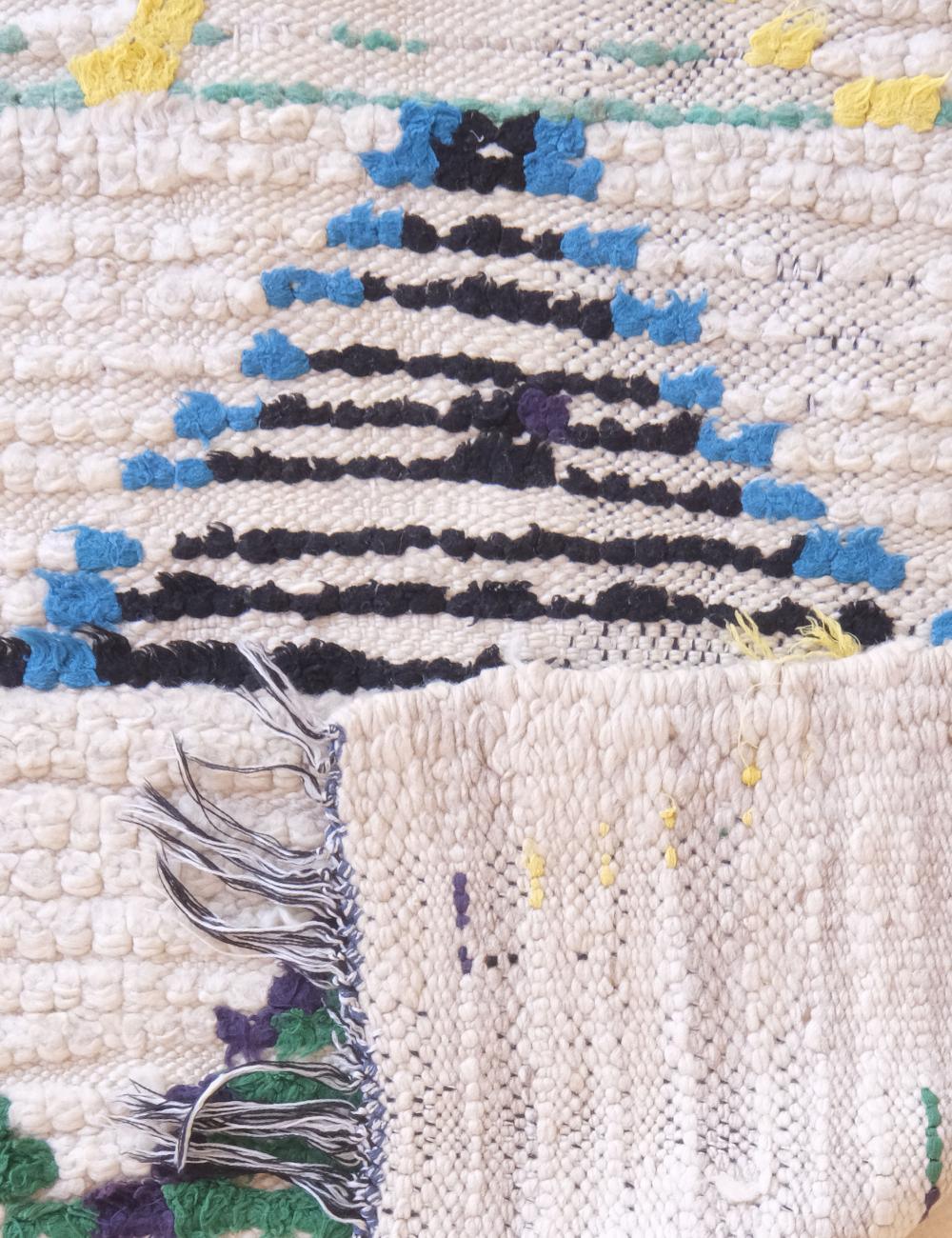 Close-up of a textured rug with geometric pattern and tassels.