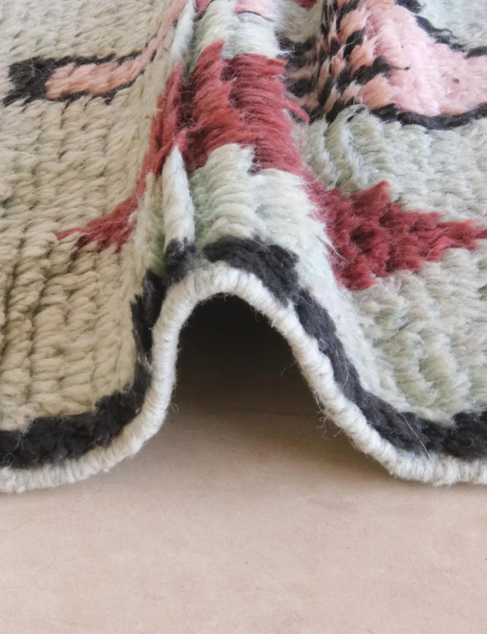 Close-up of a textured rug with floral patterns on a beige surface