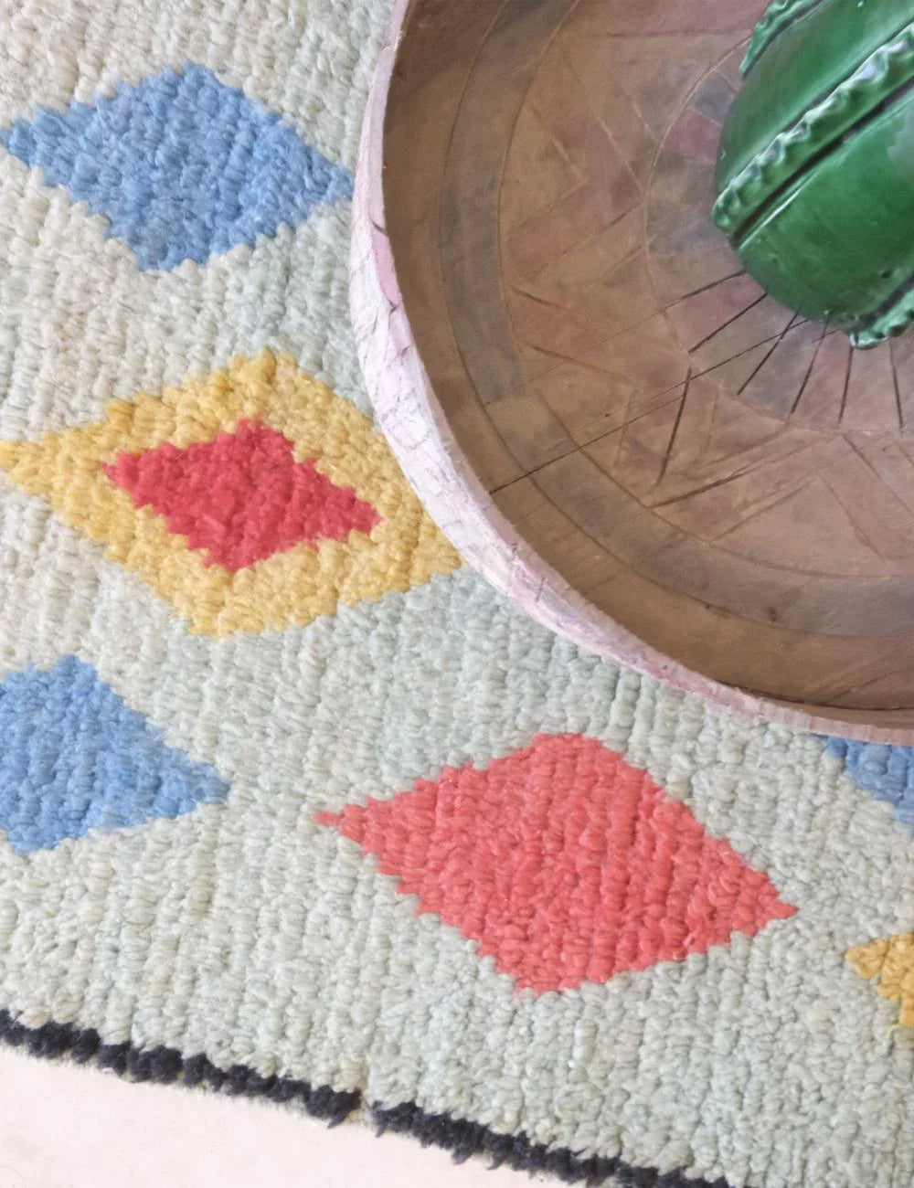Colorful geometric-patterned rug with a wooden table corner.