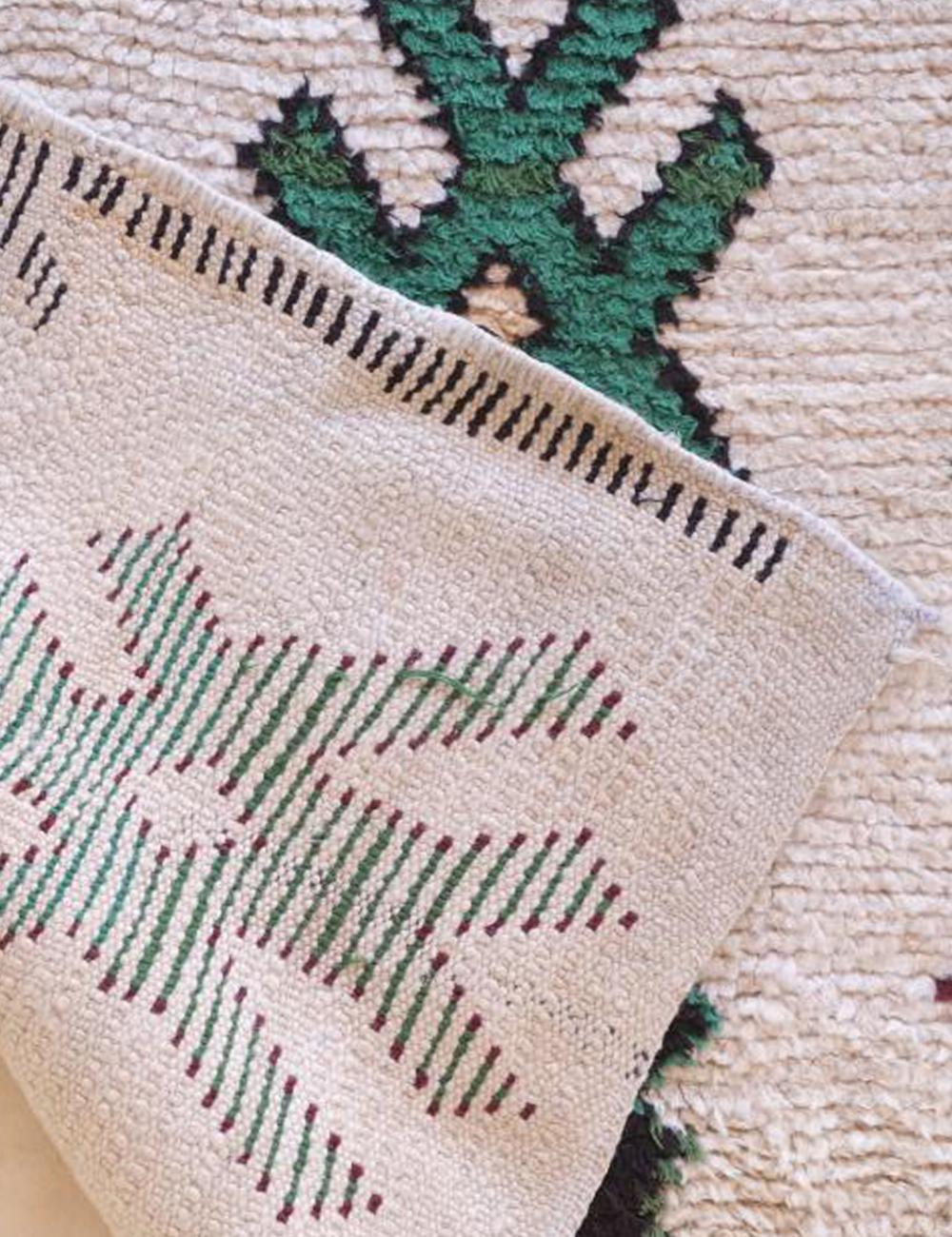 Close-up of a textured fabric with geometric patterns in green, red, and beige.