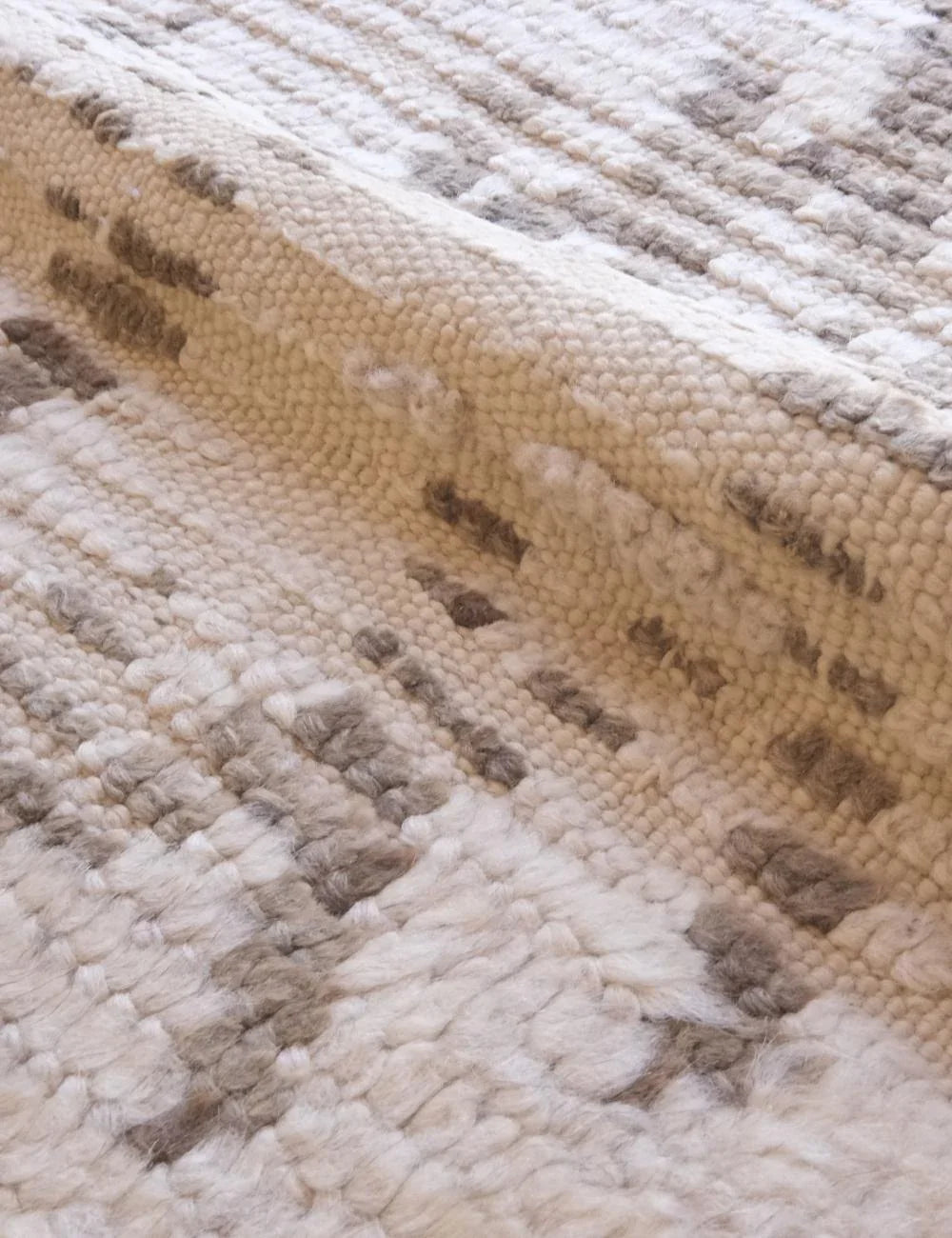 Close-up of a textured beige and brown rug with a diamond pattern.