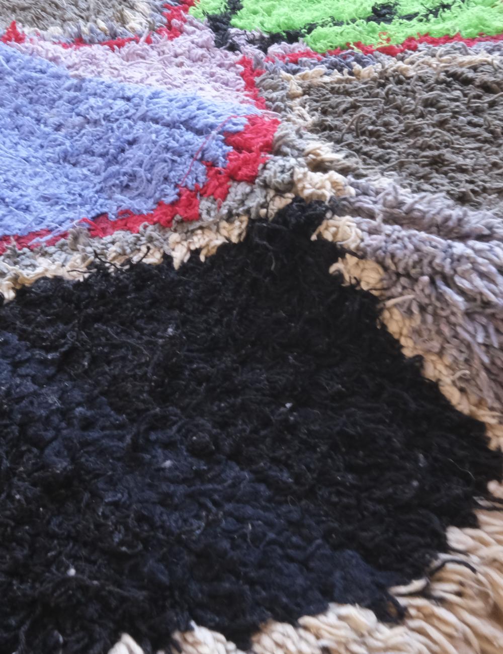 Close-up of a textured rug with various colors and patterns.