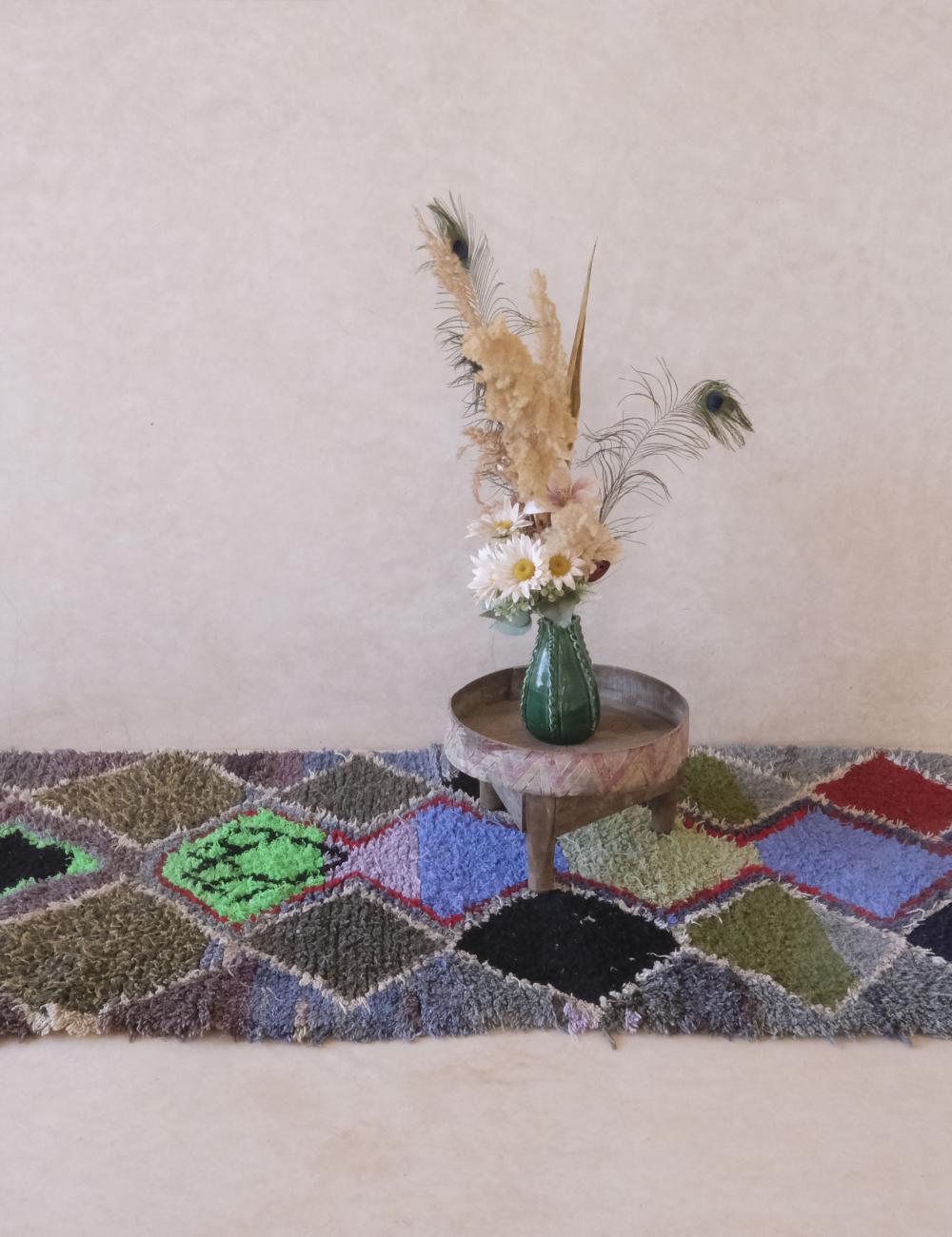 Geometric patterned rug with a small round table and vase with flowers on a light background