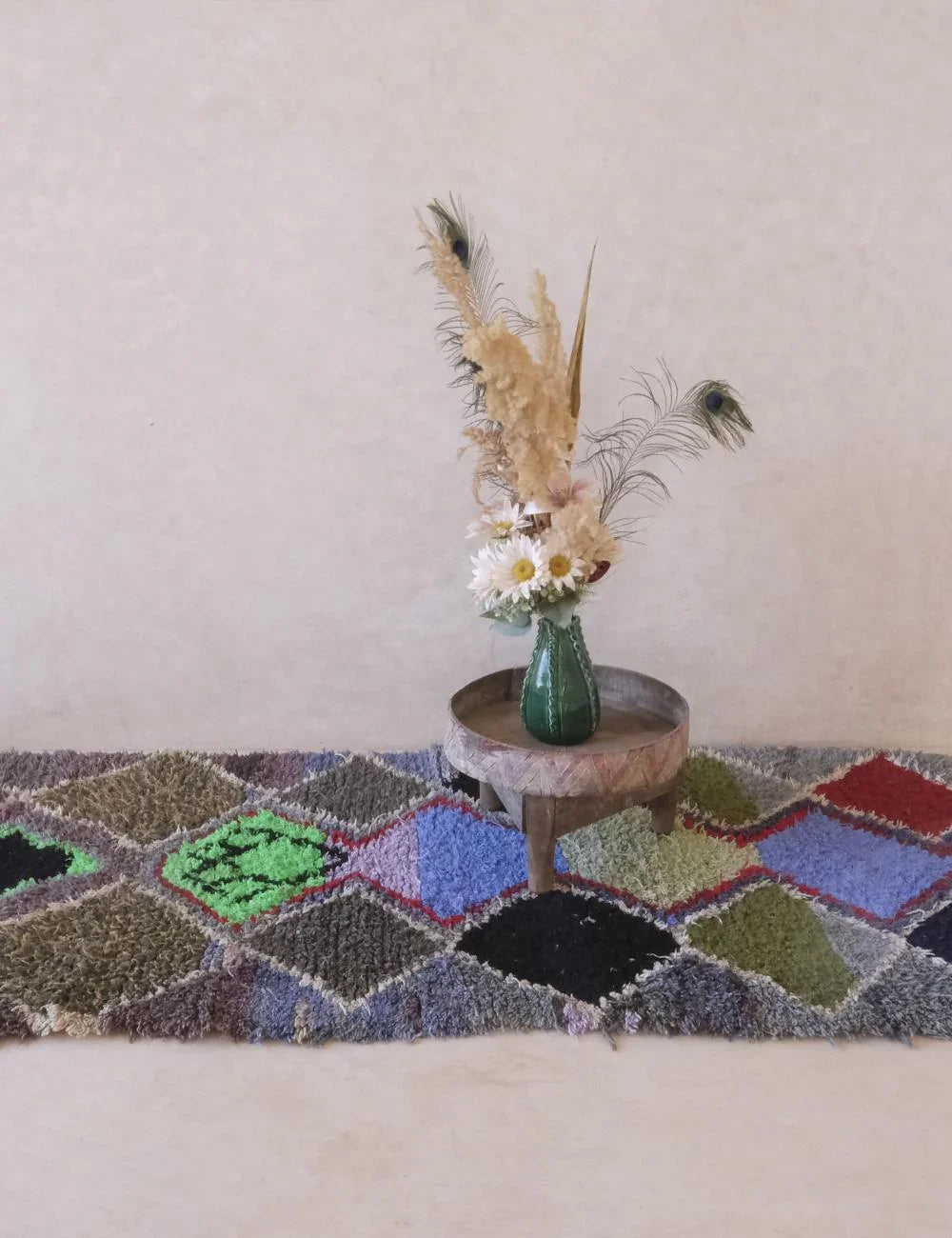 Geometric patterned rug with a small round table and vase with flowers on a light background