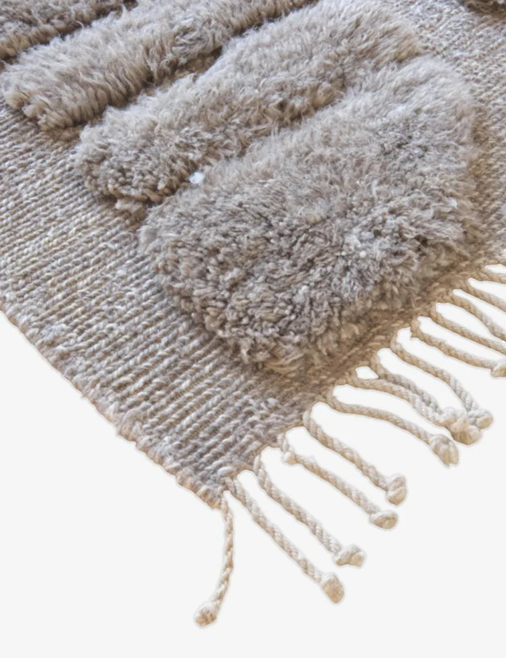 Beige textured rug with fringe on a white background