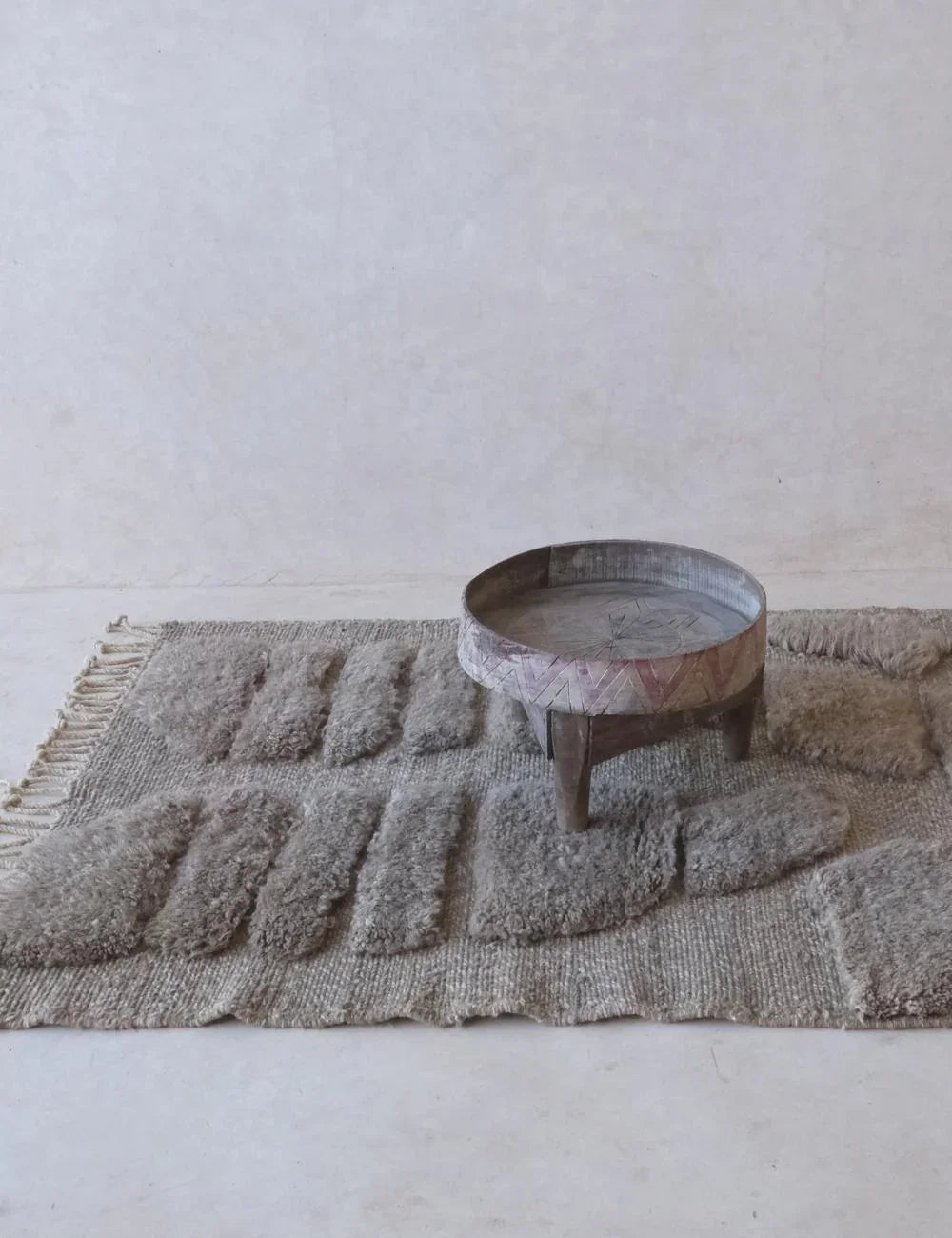 Textured rug with a small round table on a plain background