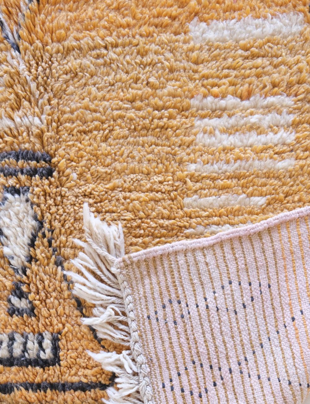 Close-up of a textured rug with a focus on the corner and fringe.