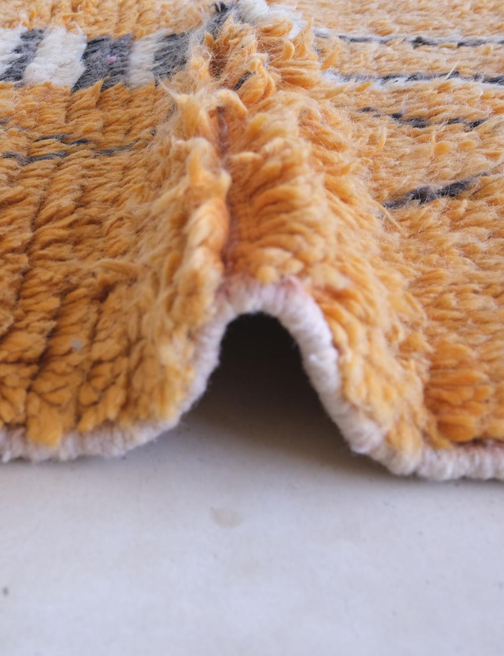 Close-up of a textured orange fabric with a white border on a light gray background