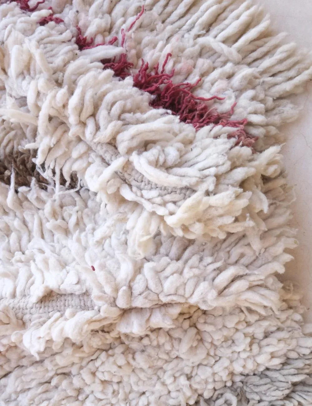 Close-up of a white mop head with red fibers on a white background