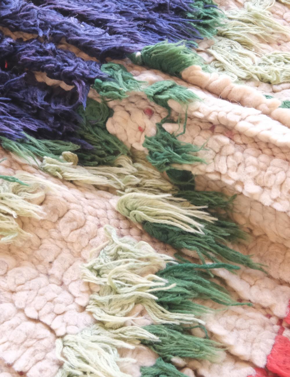 Close-up of a textured fabric with green and purple yarn.