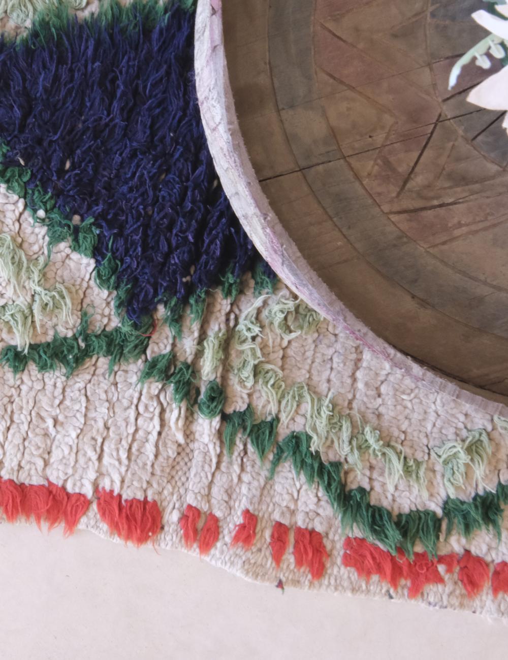 Close-up of a textured rug with colorful patterns on a wooden floor.