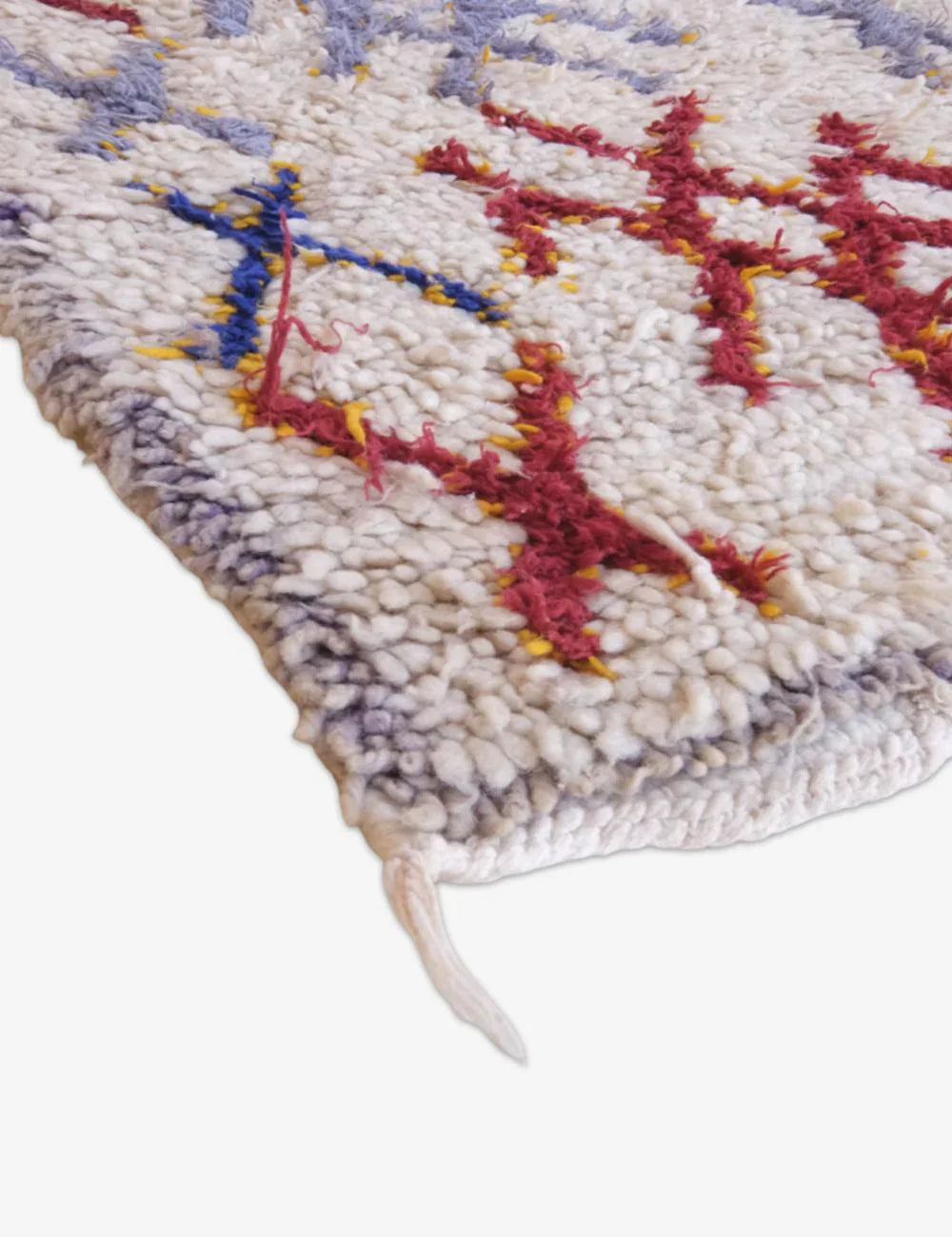 Close-up of a textured rug with colorful geometric pattern on a white background