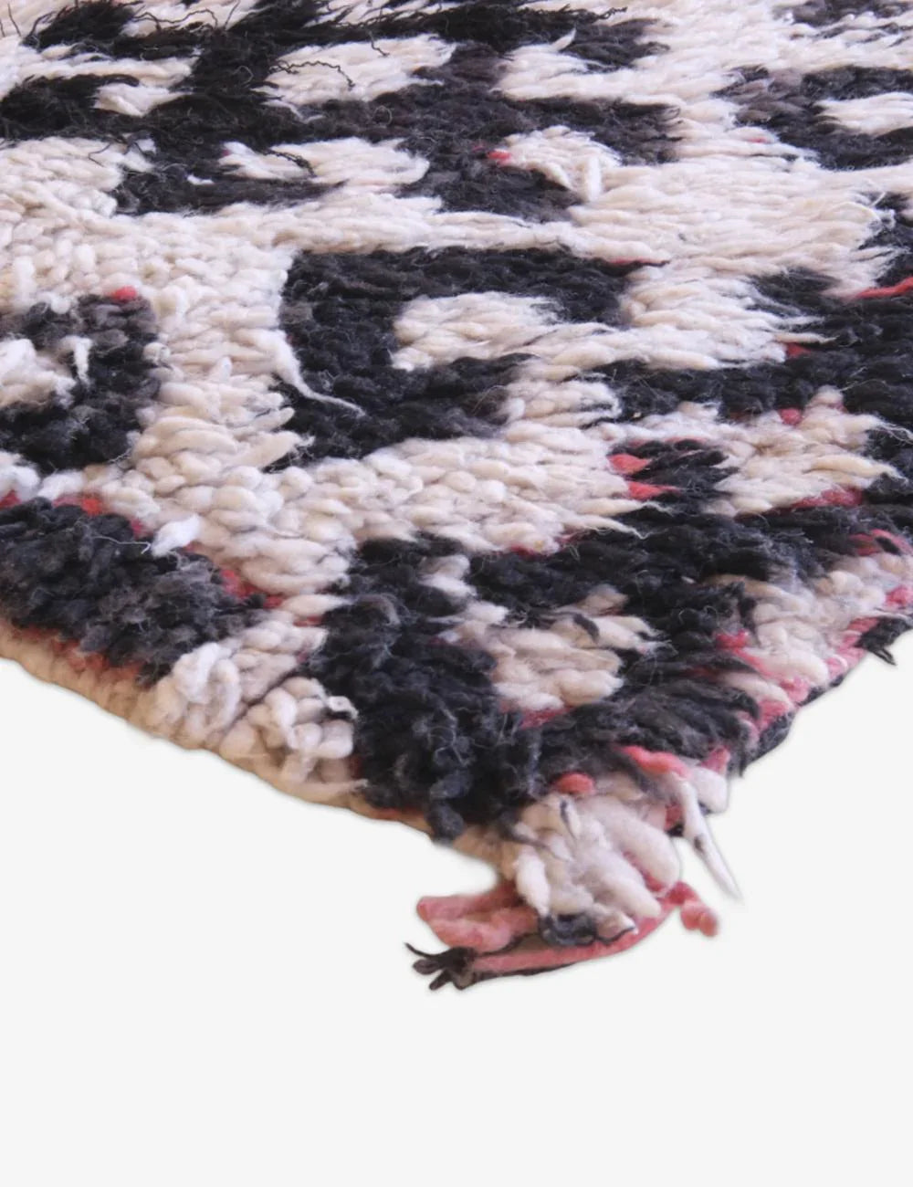 Close-up of a textured rug with black and white pattern on a white background
