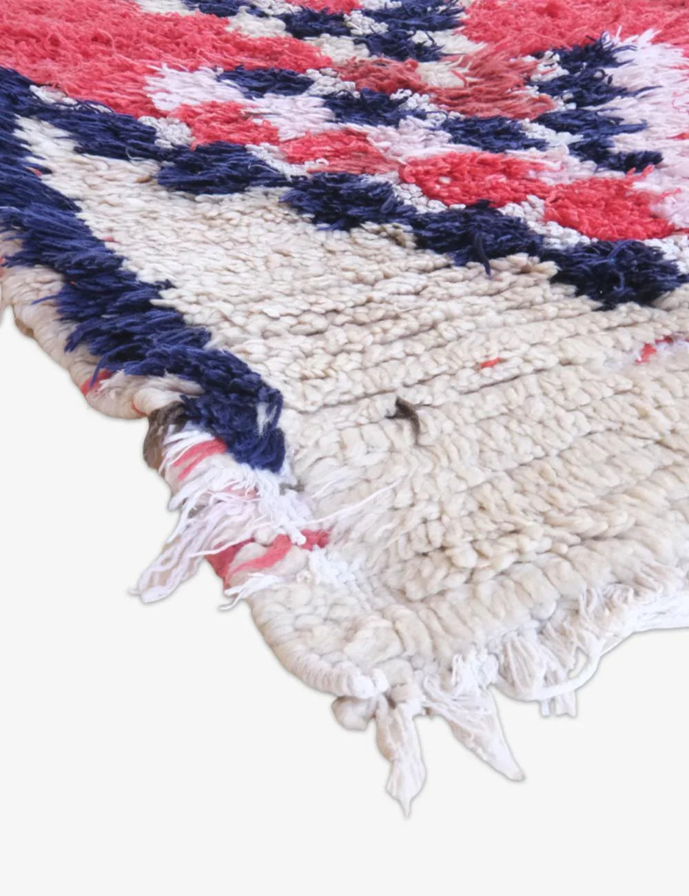Close-up of a textured rug with red, blue, and white patterns on a white background