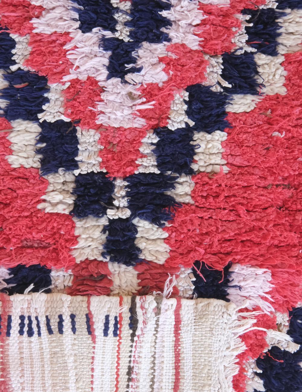 Close-up of a textured rug with red, blue, and white pattern