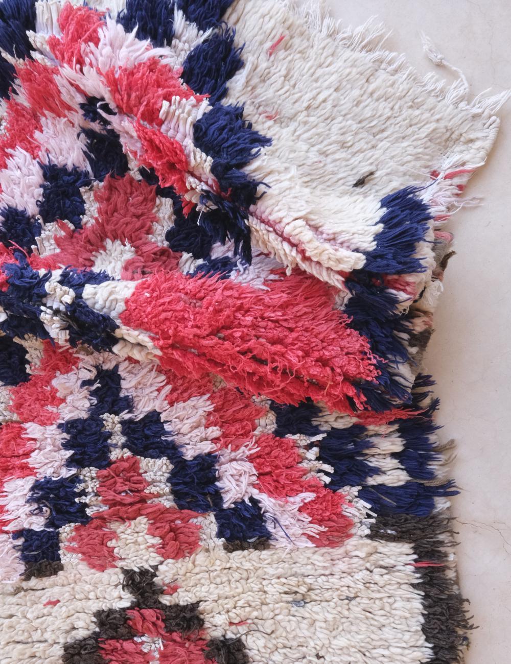 Close-up of a textured fabric with red, blue, and white pattern on a white background