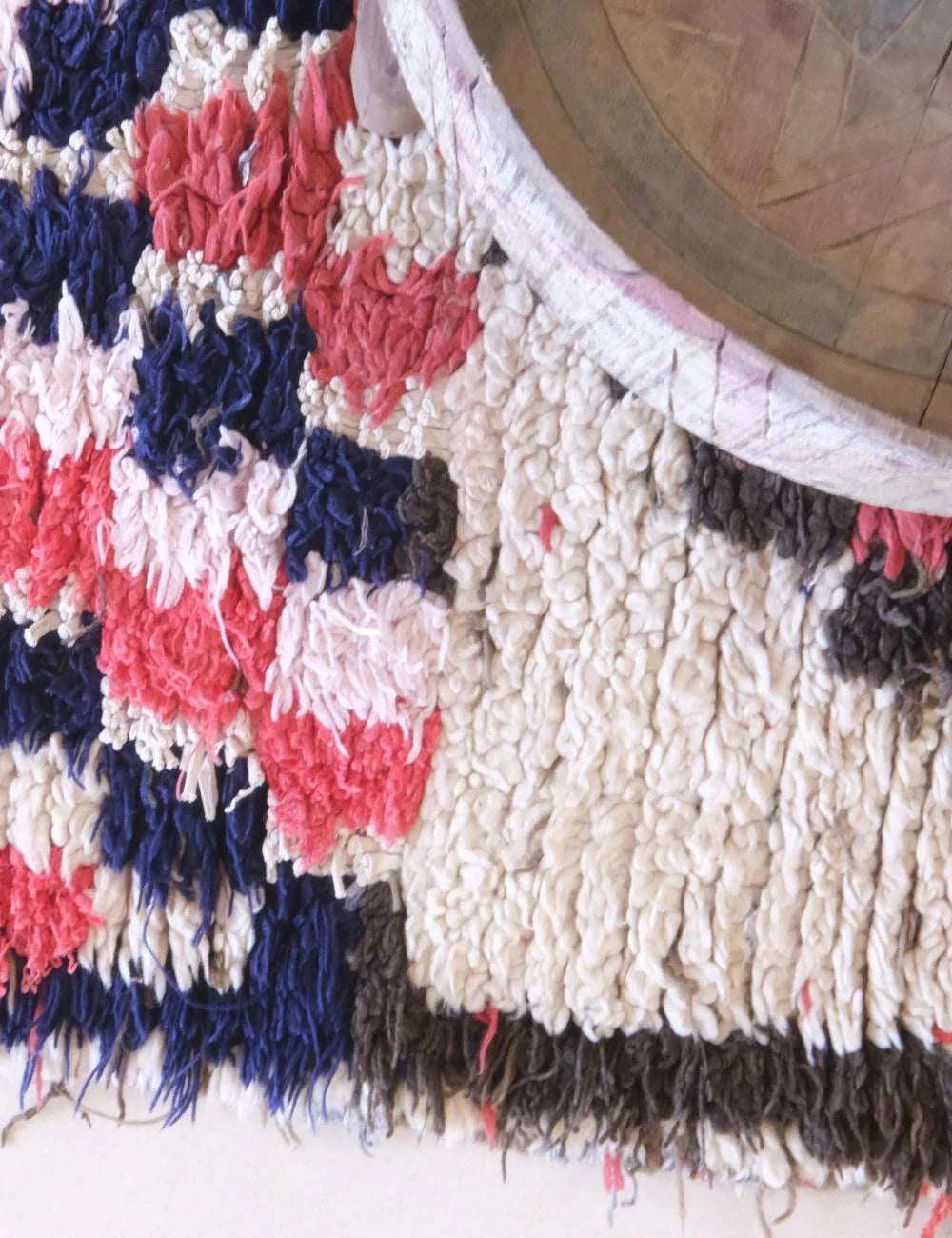 Close-up of a textured rug with geometric pattern on a wooden floor.
