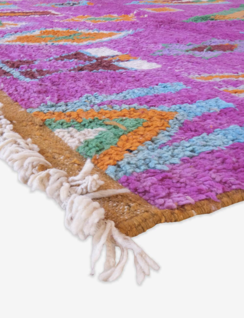 Colorful geometric-patterned rug with tassels on a white background