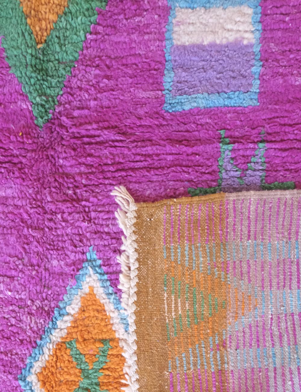 Close-up of a colorful woven fabric with geometric patterns on a pink background.