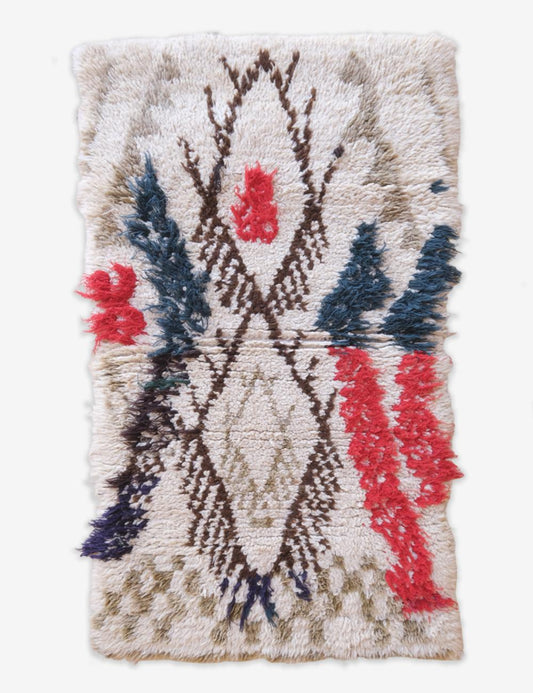 Textured rug with geometric pattern featuring red, blue, and beige colors on a white background